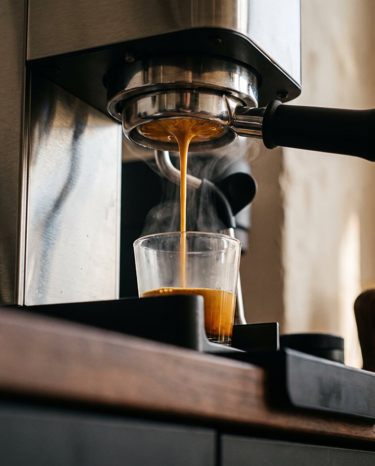 Espresso extracting from a bottomless portafilter into a glass.